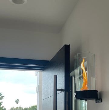 Wall Mounted Lotus Fire Torch Lamp - metal and glass designer torch light mounted on interior wall of luxury home next to a large modern wood door
