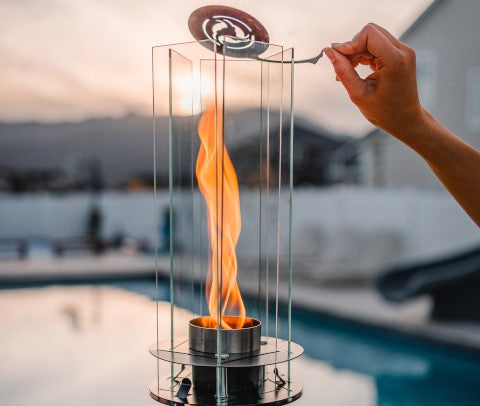 Vortek The Ultimate Tiki Torch - metal and glass designer tiki torch with vortex flame against luxury pool in the background