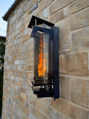 Vortex fire torches lt up at night mounted on a pool waterfall