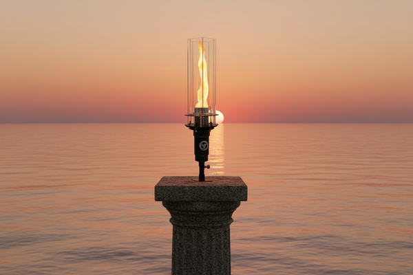 Flickering flame on a pedestal against a sunset over water