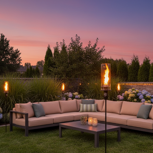 Outdoor patio setting with a sectional sofa, coffee table, and lit torches against a sunset sky.