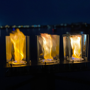 Three flame lamps on a dark background with blurred lights in the distance
