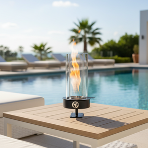 Fire pit table with flame on a patio near a pool and lounge chairs