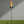 Garden torch with flame on a grassy area against a gray wall