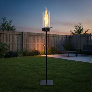 Outdoor garden torch with flame on a grassy lawn at dusk.