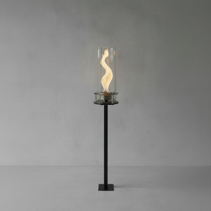 Tall black torch with flames inside a glass container on a gray background
