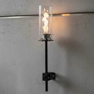 Wall-mounted candle holder with flame on a gray concrete wall