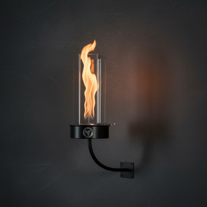 Outdoor oil wall-mount fire feature with a vertical flame enclosed in a clear glass wind guard, supported by a curved metal arm and wall plate, designed for modern patio, garden, and exterior wall lighting.