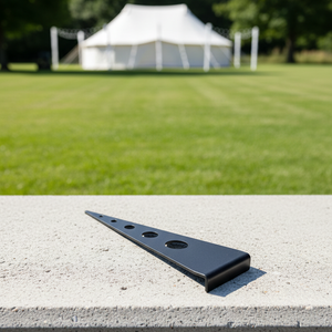 Black metal bracket on a concrete surface with a blurred outdoor background