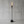 Outdoor gas tiki torch featuring a tall vertical flame, clear glass wind guard, and black metal base for modern patio, garden, and landscape lighting using propane or natural gas.
