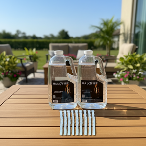 Two bottles of HaloFire torch fuel on a wooden table outdoors with a garden background.