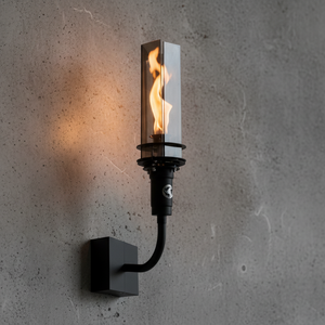Outdoor wall-mounted gas tiki torch with a tall vertical flame, clear glass wind guard, black metal wall mount arm, and rectangular wall plate, designed for modern patio, garden, and exterior wall lighting using propane or natural gas.