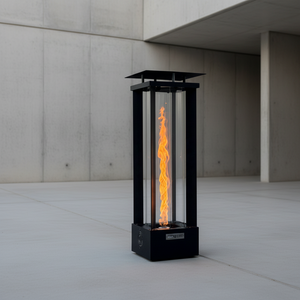 Outdoor fire pit with flames lit, placed on a patio by a body of water during sunset.