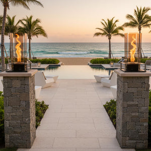 Outdoor patio with fire pits, chairs, and ocean view during sunset.
