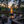 Outdoor oil tiki torch with a tall vertical flame, clear glass wind guard, and metal pole secured to a rail-mounted bracket, designed for modern patio, deck, and outdoor living spaces.