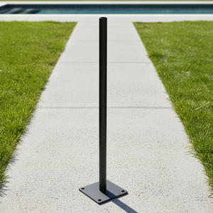 Black metal bollard on a concrete path with grass on either side, near a pool.
