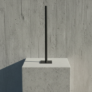 Modern outdoor light fixture on a concrete block against a concrete wall