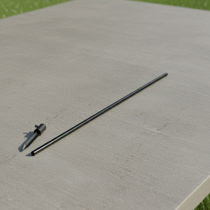 A black metal rod and ground stake on a concrete table with grass on either side