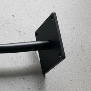 Black curved metal bracket on a gray concrete surface