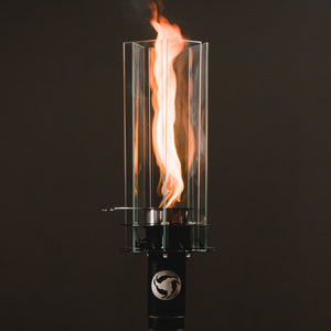 Fire torch with a black base and clear glass container on a dark background