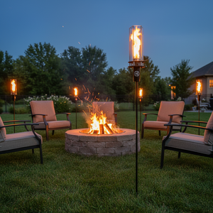 Outdoor oil tiki torch with a tall vertical flame, clear glass wind guard, and black metal post mounted on a ground stake, designed for modern patio, garden, and landscape lighting.