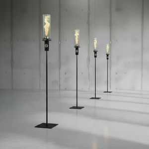 Set of four tall floor lamps with flame-like lights on a reflective surface.
