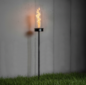 Torch-style outdoor light on grass with a plain wall background