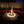 Fire pit with flames at night in an outdoor setting with red cushions and palm trees.