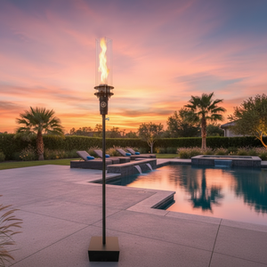 Outdoor gas tiki torch featuring a tall vertical flame, clear glass wind guard, and black metal base for modern patio, garden, and landscape lighting using propane or natural gas.