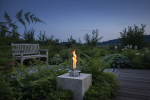 Modern outdoor fireplace with flames on a concrete surface and gray background