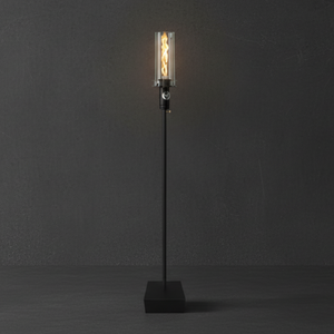 Outdoor gas tiki torch with a tall vertical flame, clear glass wind guard, slim black metal post, and square weighted base, designed for modern patio, garden, and landscape lighting using propane or natural gas.