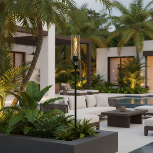 Outdoor gas tiki torch with a tall vertical flame, clear glass wind guard, slim black metal post, and square weighted base, designed for modern patio, garden, and landscape lighting using propane or natural gas.